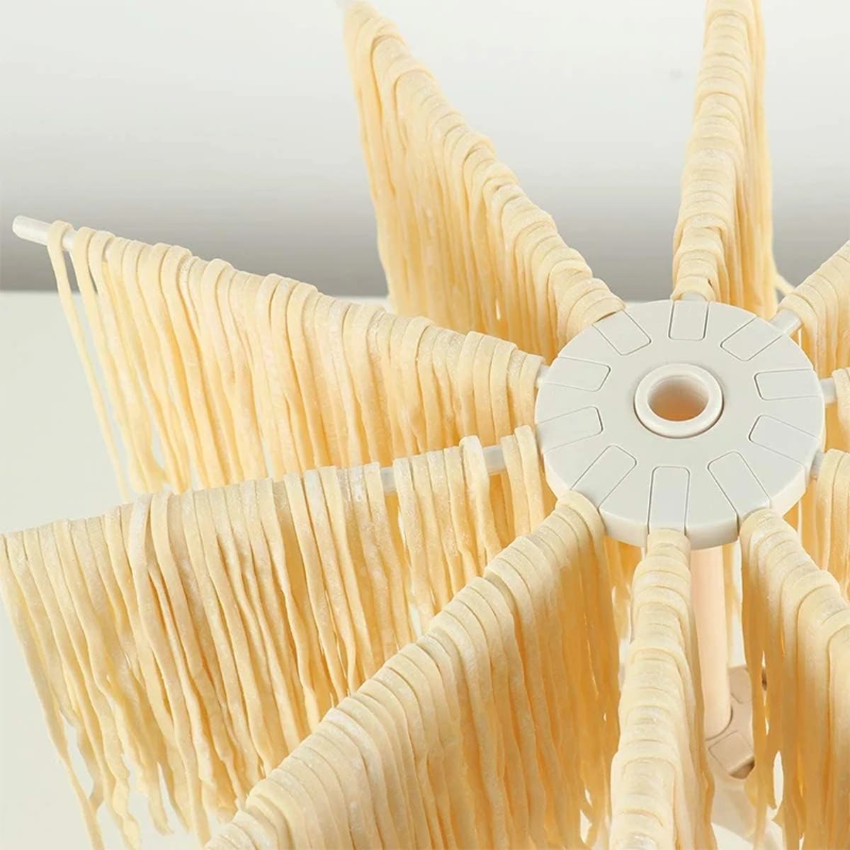 Nærbilde av navet på pastastativet med armer fulle av fersk spagetti