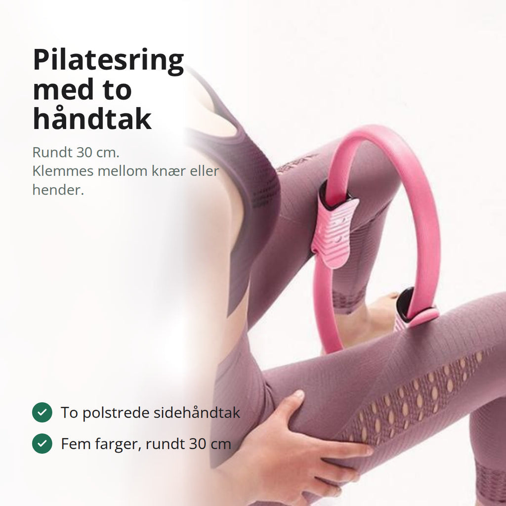 Pilatesring i sort med to polstrede sidehåndtak, liggende på en grå treningsmatte