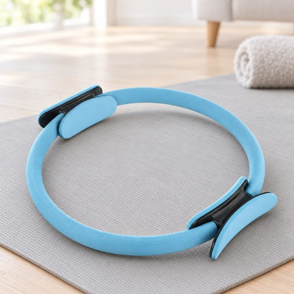 Blå pilatesring med polstrede håndtak på en grå matte