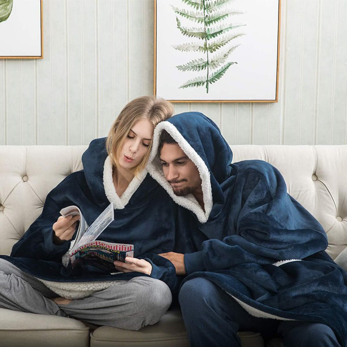 To personer i blå pleddgenser som leser i en sofa