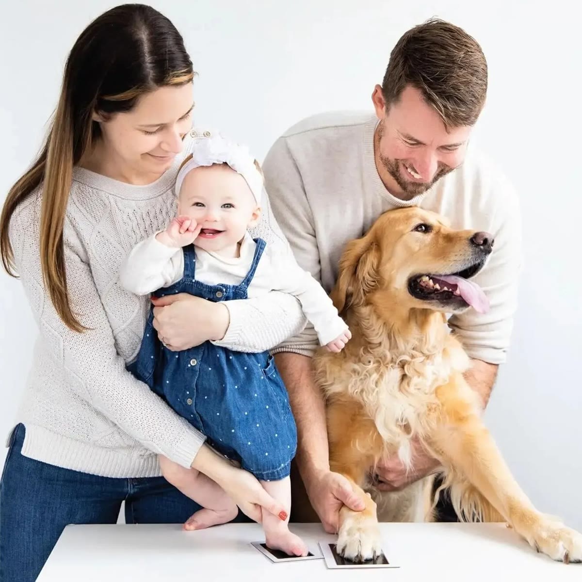 Familie med baby og golden retriever som lager avtrykk av hånd og pote