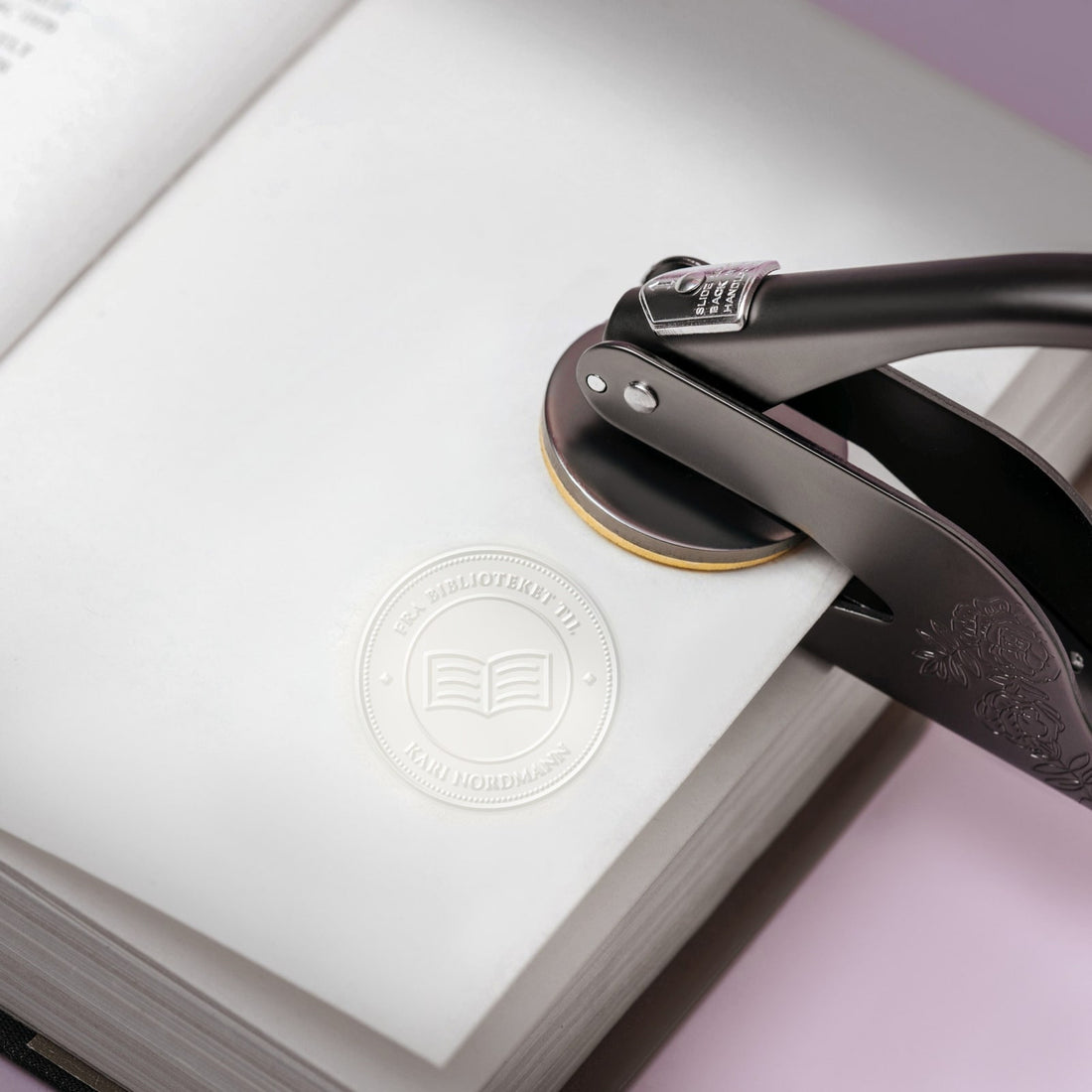 Prega pregetang på en åpen bok med et opphøyd ex libris