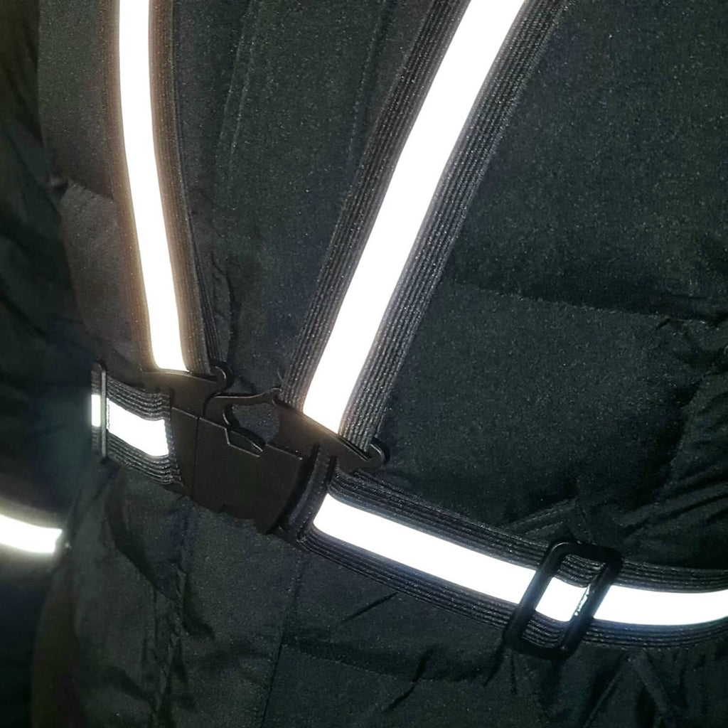 Refleksvesten festet over en mørk vinterjakke, med spennen synlig