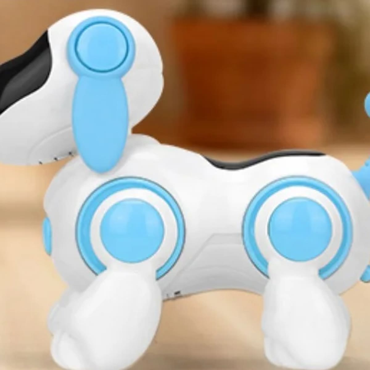 Robothunden sett fra siden, med lyseblått øre, lyseblå ledd på bena og en hale med kule i enden