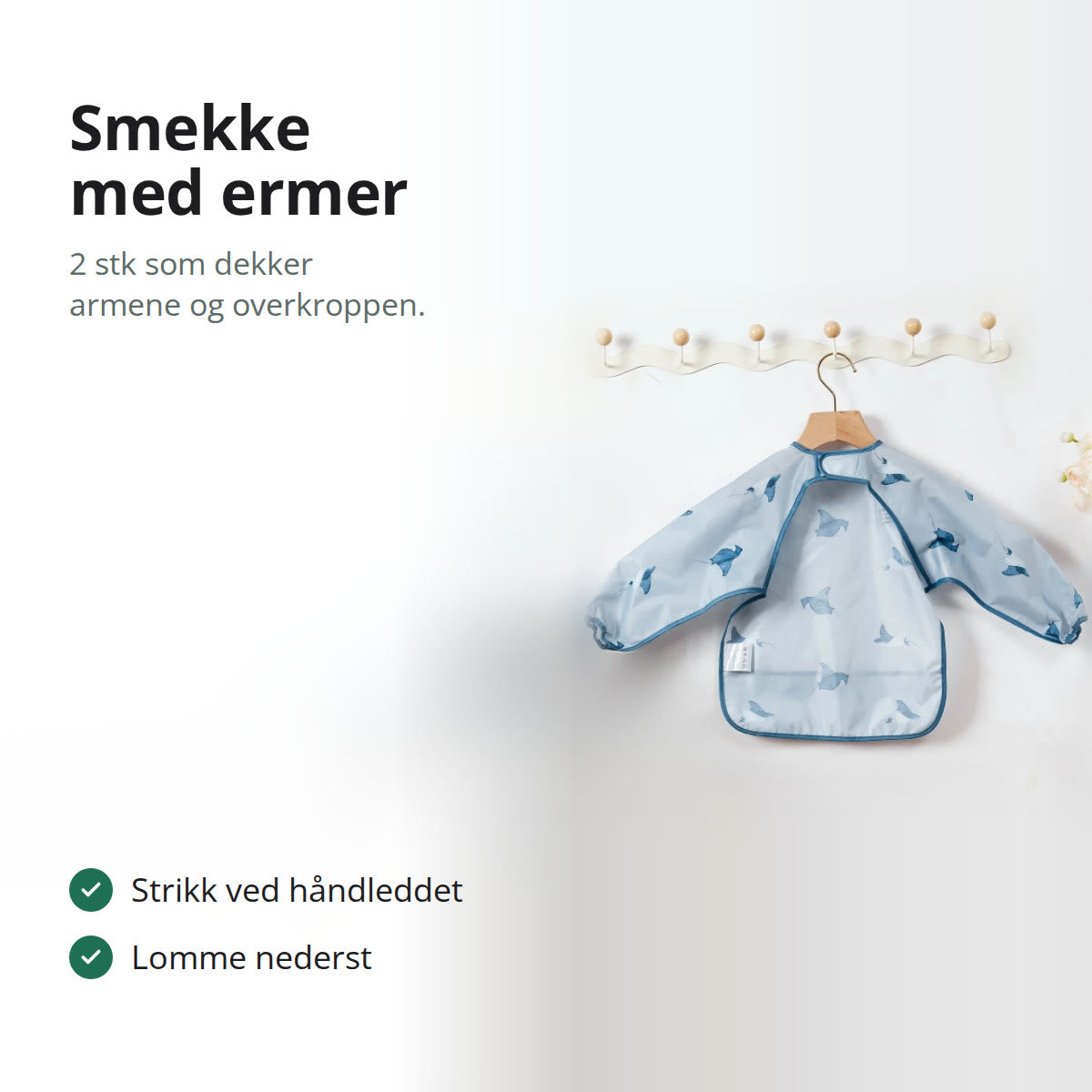 Lyseblå smekke med lange ermer og rokkemønster som henger på en kleshenger