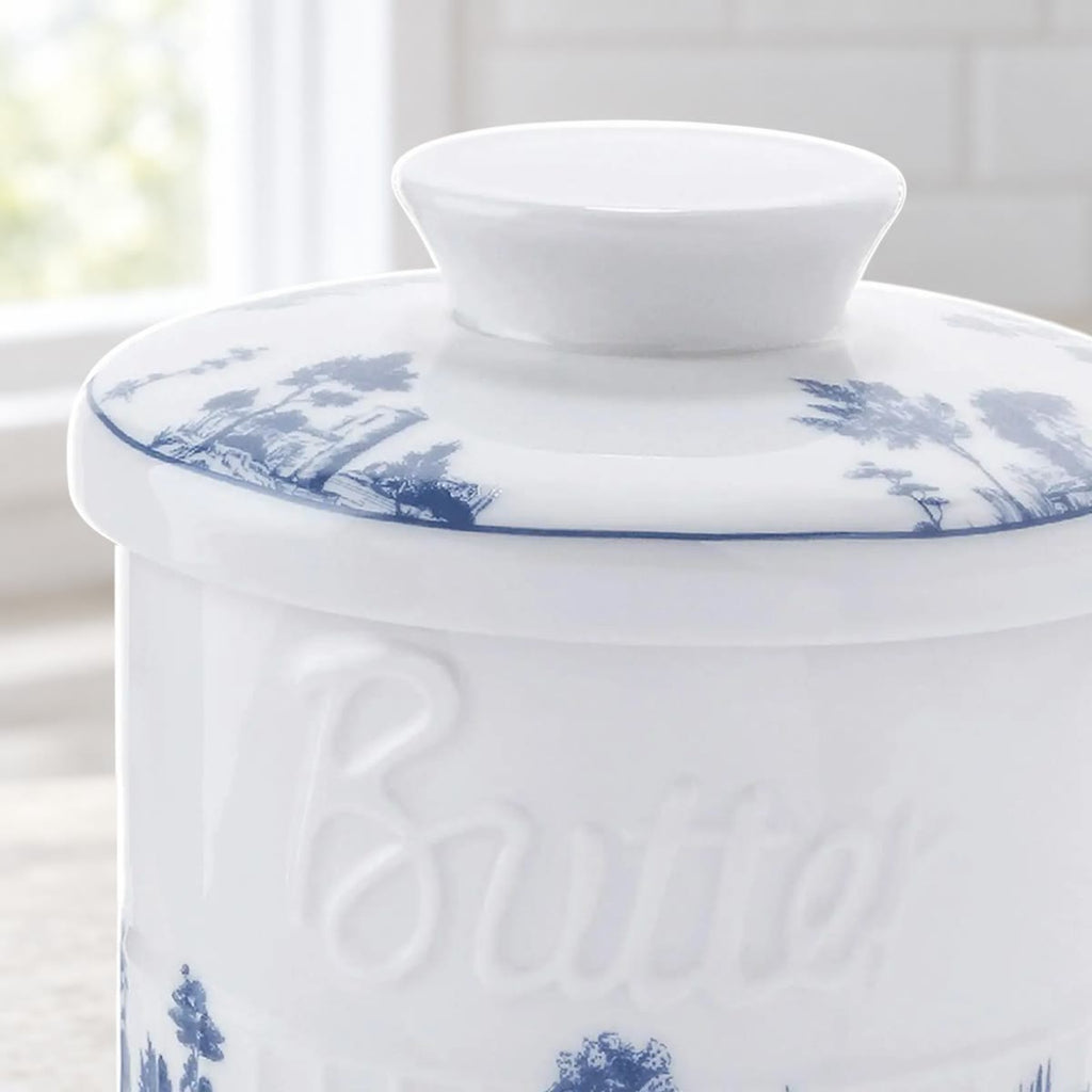 Nærbilde av lokket med knott og blått landskapsmotiv, og av ordet Butter i relieff på krukken