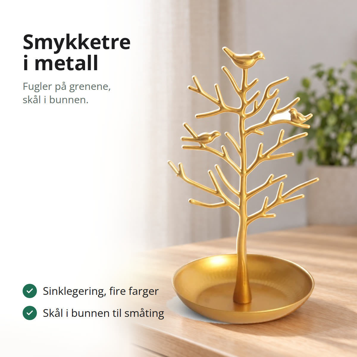 Smykketre i gullfarget metall med små fugler på grenene og en rund skål i bunnen, på en lys eikekommode