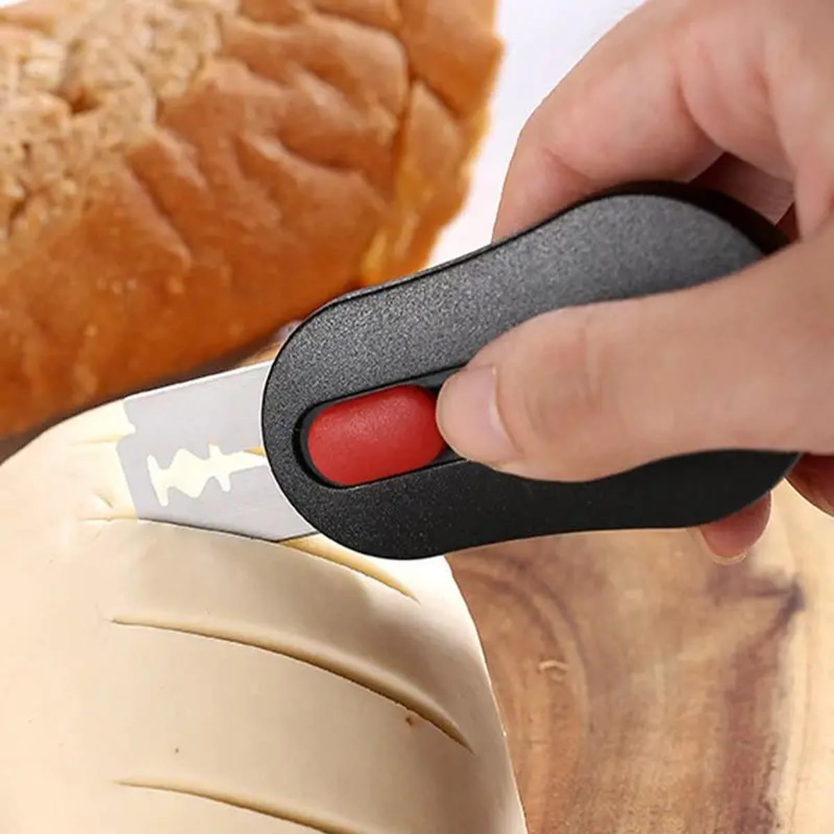 Hånd som lager et snitt i en brøddeig med snittekniven