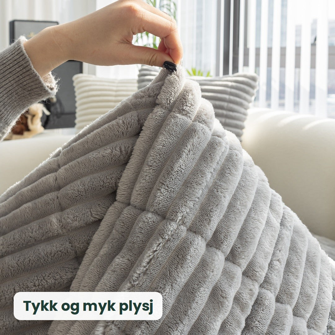 En hånd løfter Kosla-trekket og viser den tykke, myke plysjen
