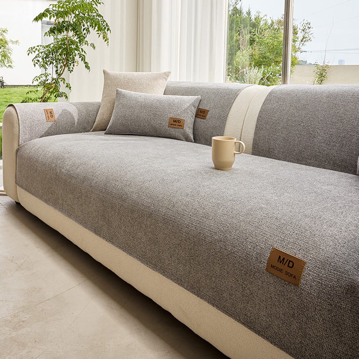 Lys grått sofatrekk lagt over seteputen på en tresetes sofa