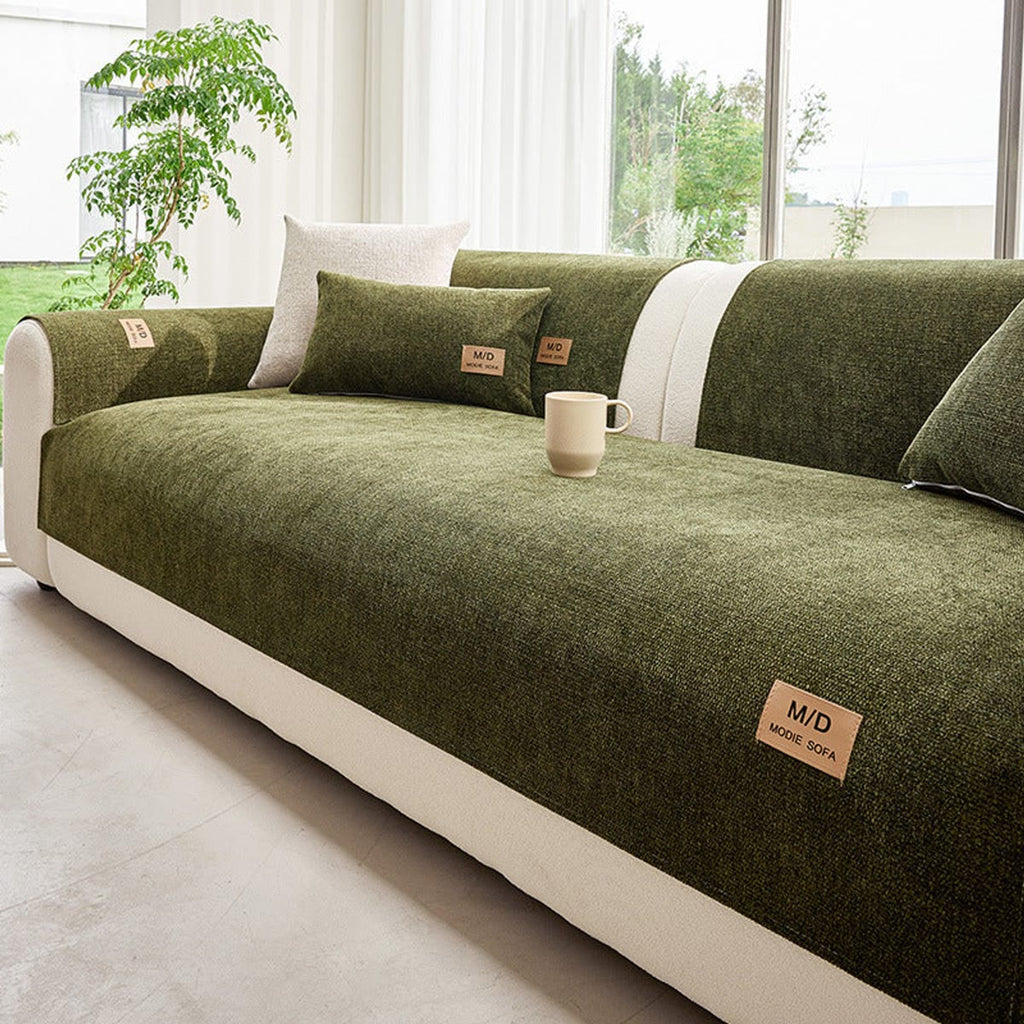 Grønt sofatrekk lagt over seteputen på en sofa med hvite puter