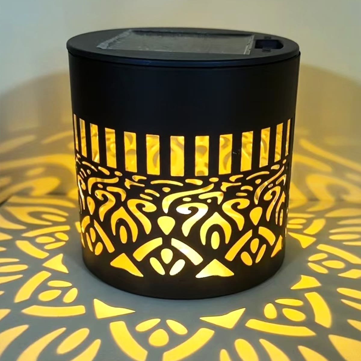 Nærbilde av lampen med solcellepanelet på toppen og det utskårne mønsteret