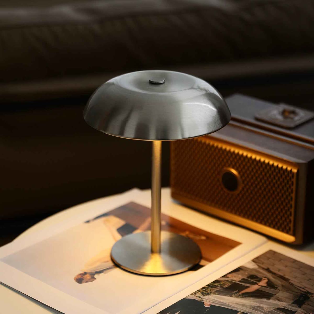 Sopplampe i børstet metall tent på et bord ved siden av en gammel radio og gamle fotografier