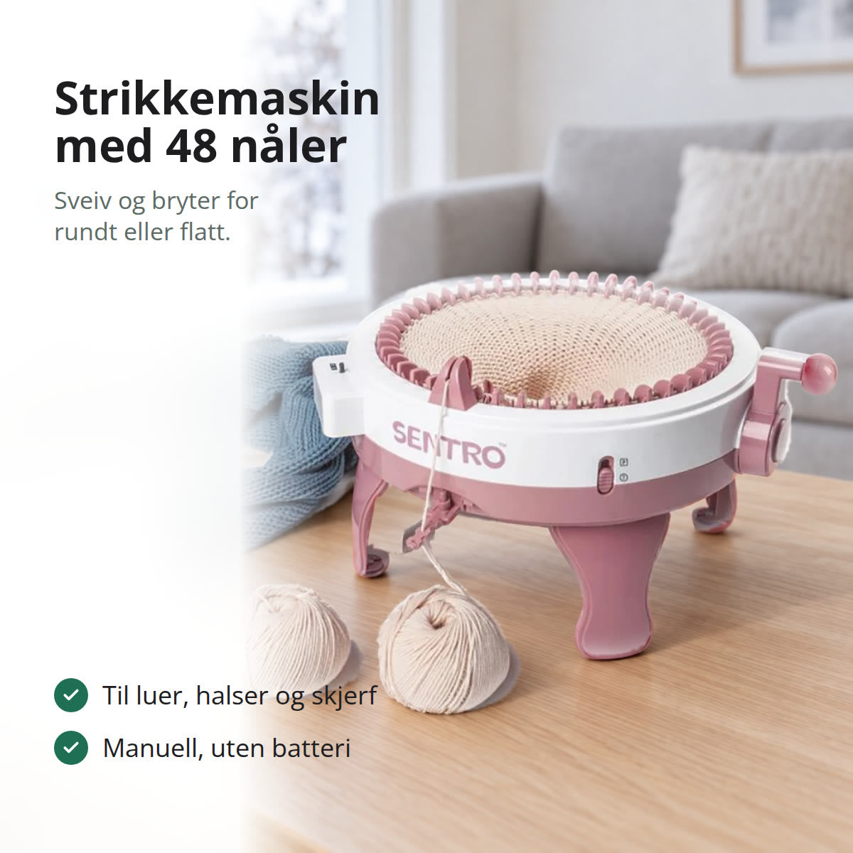Rosa og hvit strikkemaskin med 48 nåler og sveiv, med strikketøy i ringen, på et eikebord i en lys stue med vindu mot snø