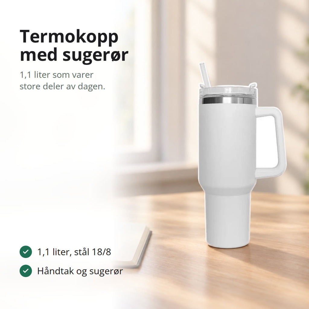 Hvit termokopp med håndtak og sugerør på et lyst skrivebord ved et vindu