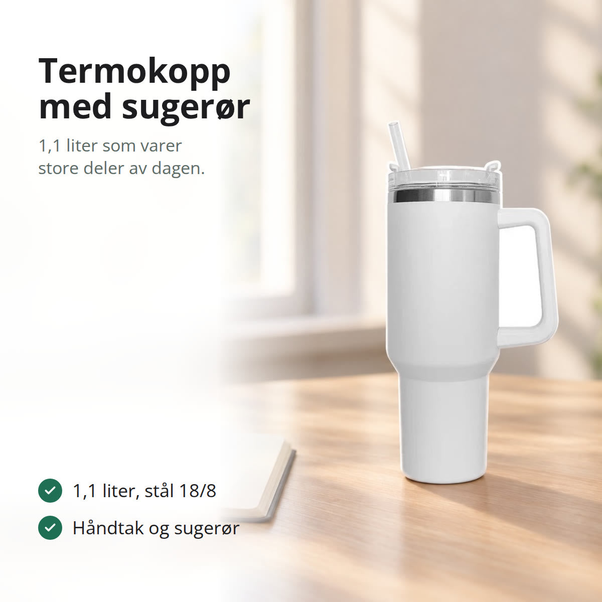 Hvit termokopp med håndtak og sugerør på et lyst skrivebord ved et vindu