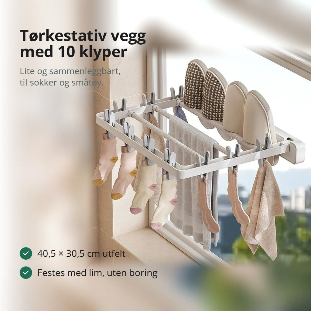 Hvitt tørkestativ til vegg, felt ut ved et vindu, med sokker i klypene, et håndkle over stengene og tøfler oppå