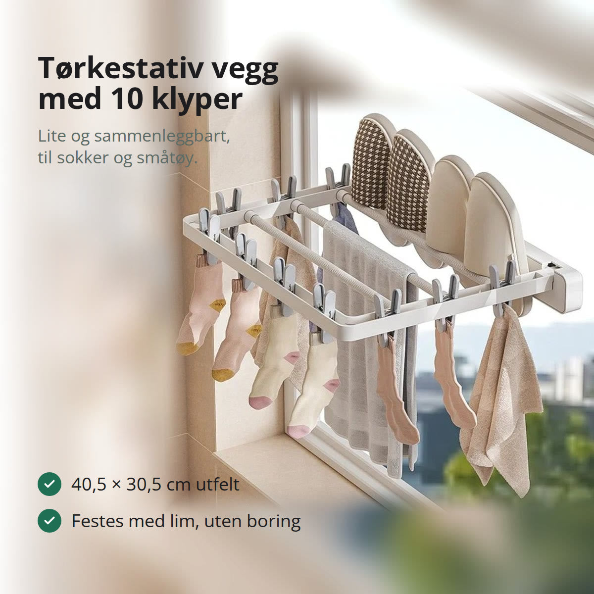 Hvitt tørkestativ til vegg, felt ut ved et vindu, med sokker i klypene, et håndkle over stengene og tøfler oppå