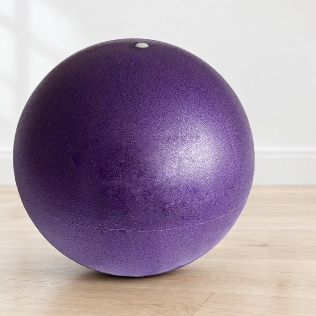 Lilla pilatesball med ventil i toppen, på lyst gulv