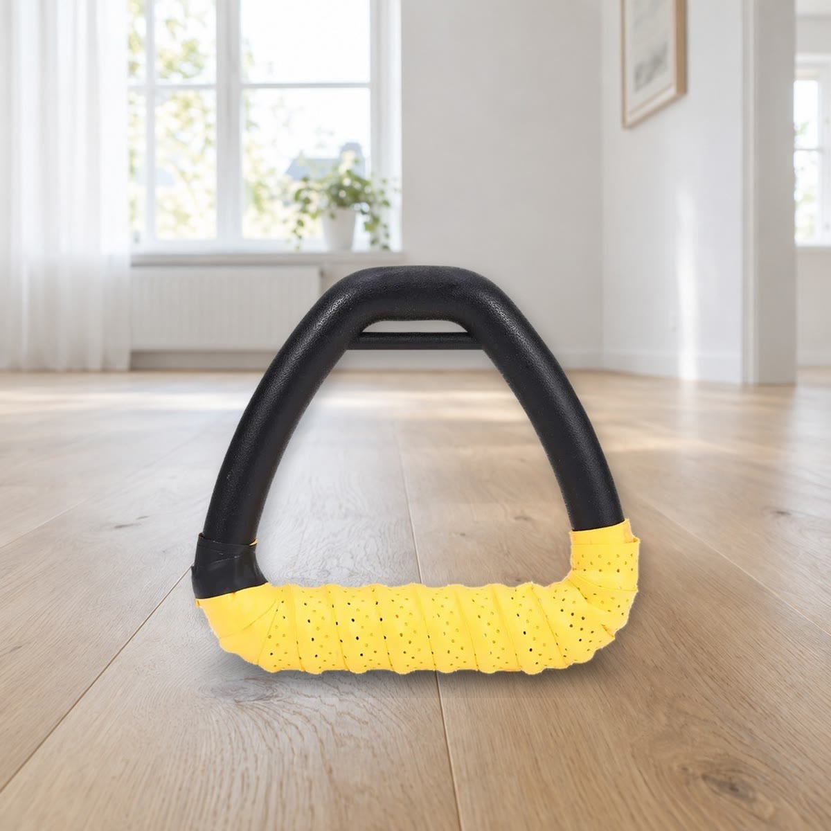 Ett trekantet håndtak med gul griptape surret rundt grepet, stående på et gulv av lys eik