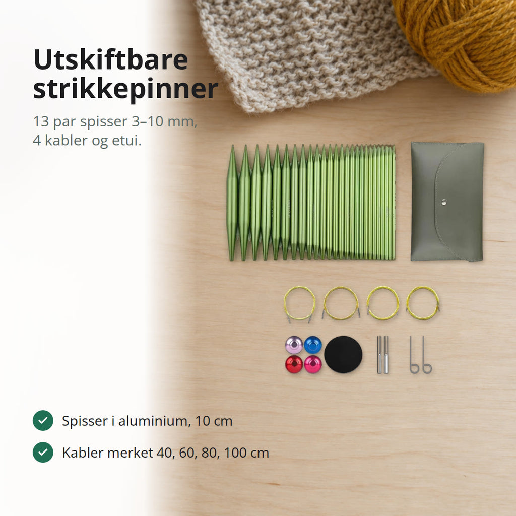 Utskiftbare strikkepinner i grønn aluminium med fire kabler, endestoppere, nøkler og etui på et lyst bord med garnnøster