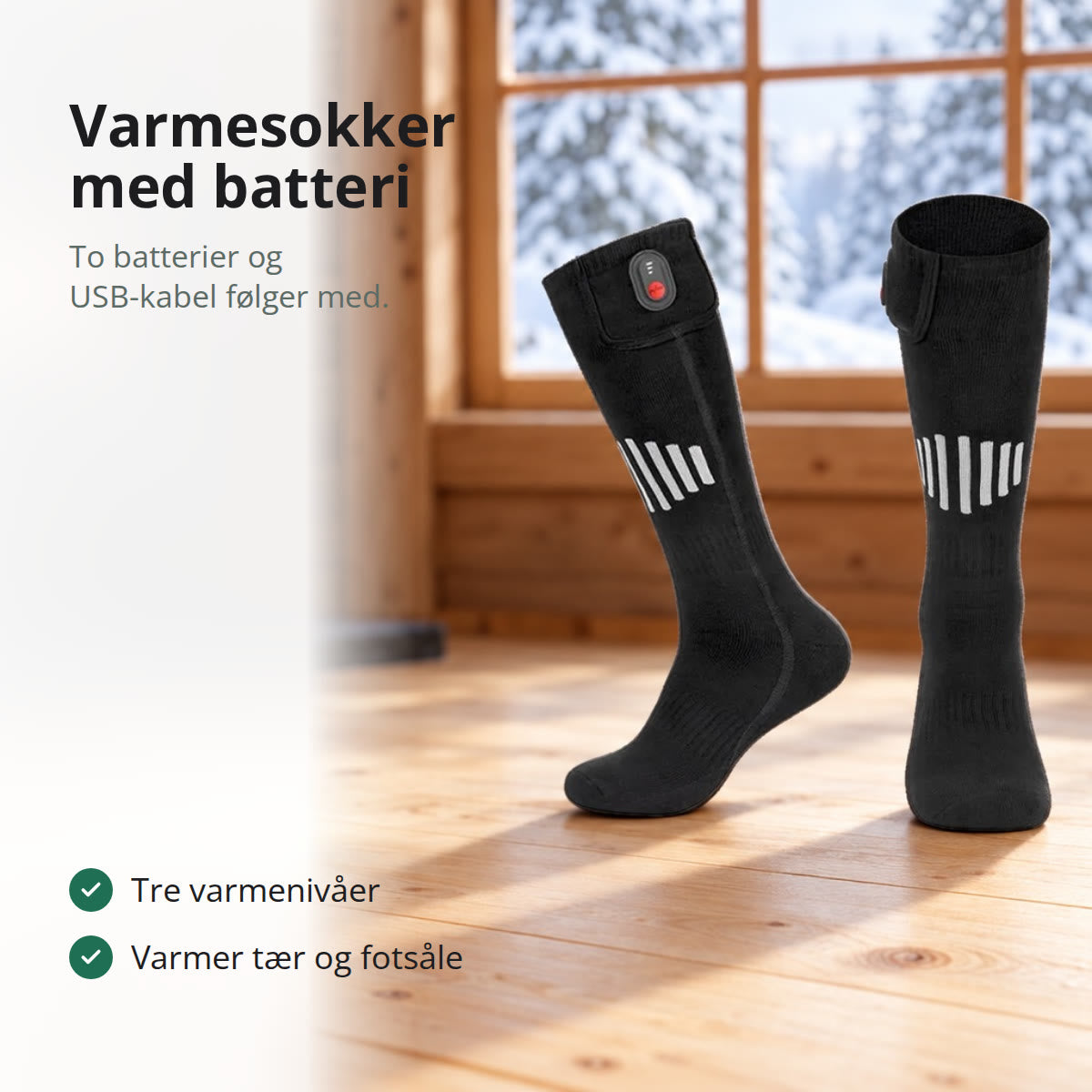 Svarte varmesokker med grå striper og knapp på batterilommen, stående på et furugulv i en hytte med vedovn og snø utenfor vinduet