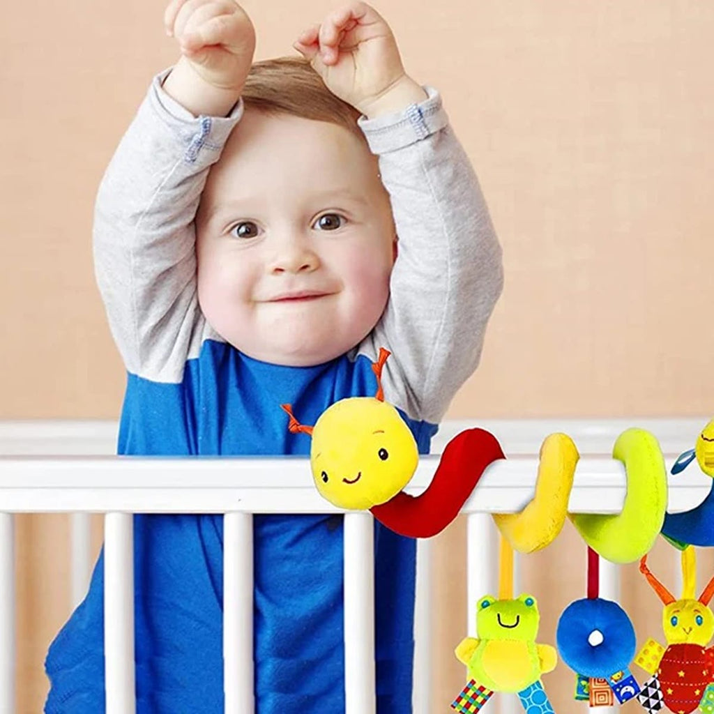 Baby som står i sengen bak en vognleke festet på sengekanten