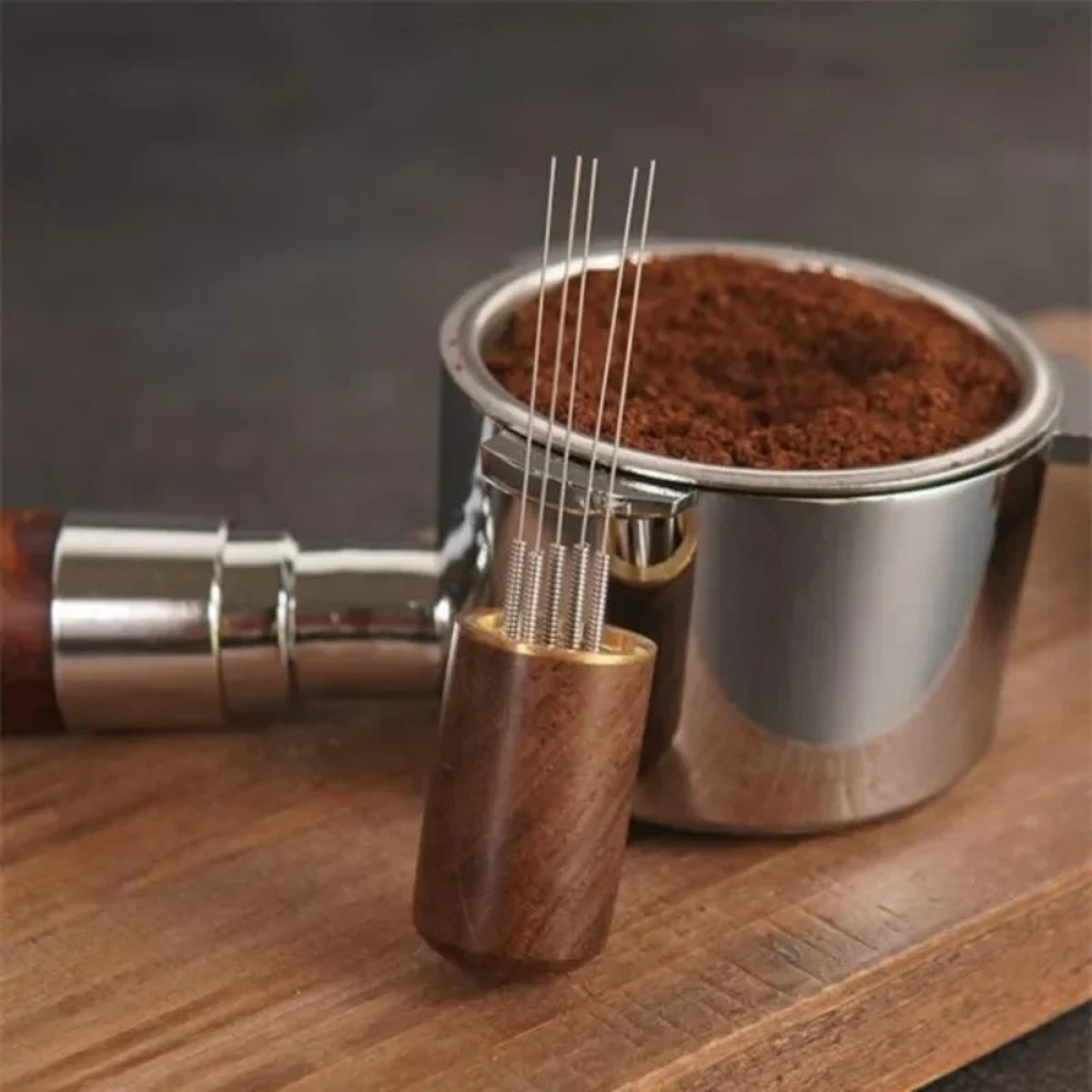 WDT-verktøy med tynne nåler og håndtak i tre foran en filterkurv med kaffepulver