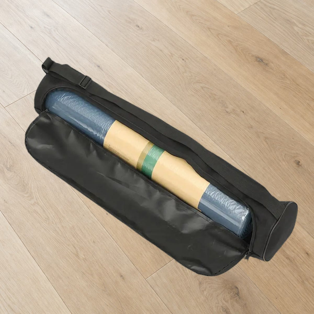 Svart yogamatte bag åpnet langs siden med en rullet yogamatte inni, på et eikegulv (matten følger ikke med)